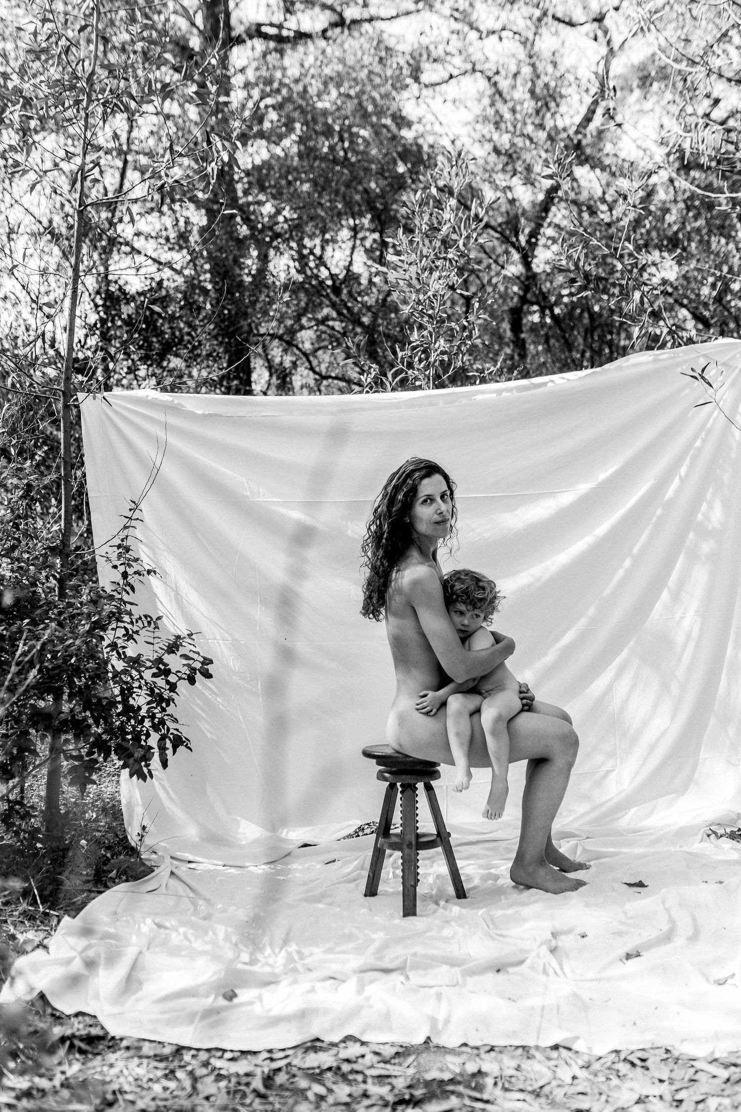 Black and white artistic portrait on white backdrop with natural forest setting in background.