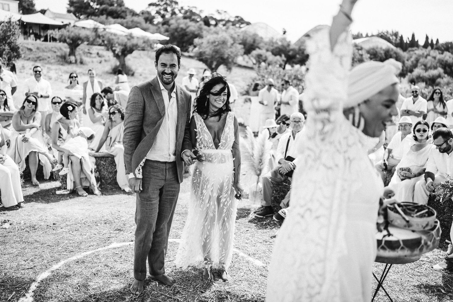 Wedding party celebrates outdoors with joyful dancing and laughter at a sunny garden reception.