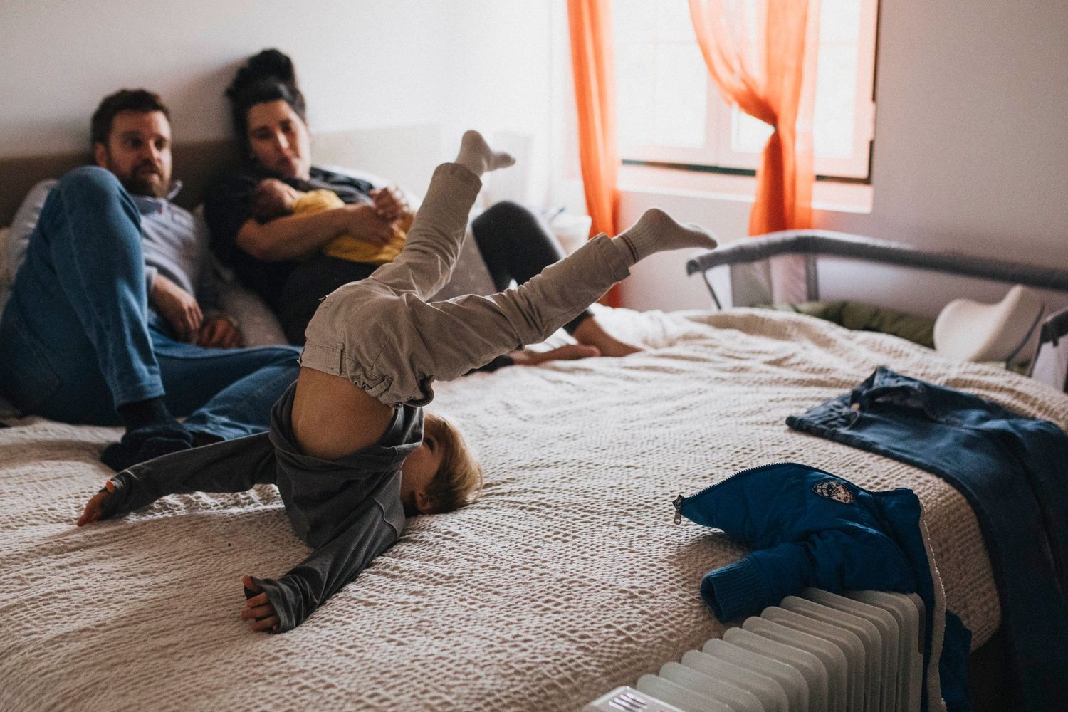 Family members lounging together on a bed in casual intimate moments.