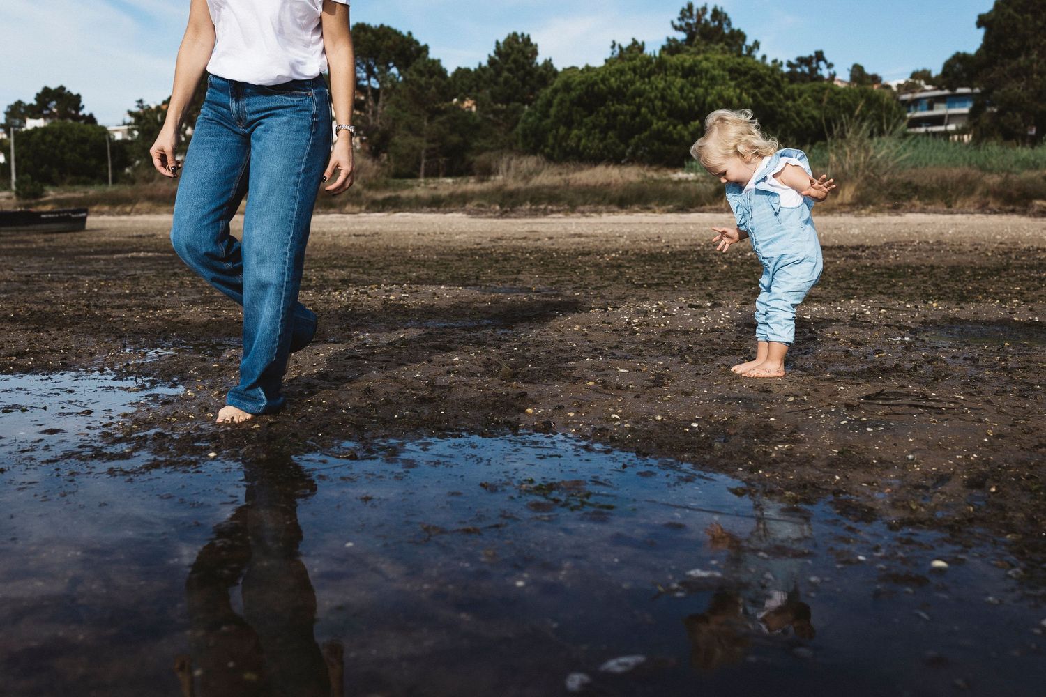 A sequence of playful moments at a beach shoreline shows someone splashing and exploring the shallow water.