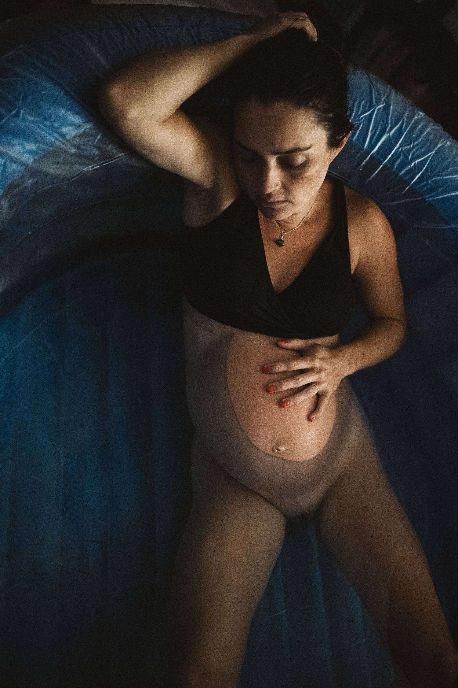 Artistic boudoir photography series showing intimate body silhouettes against dark blue bedding in moody lighting.