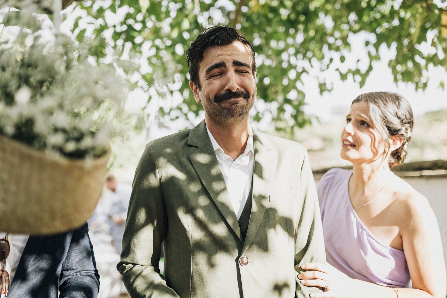Romantic outdoor wedding ceremony with a couple sharing intimate moments under green trees.