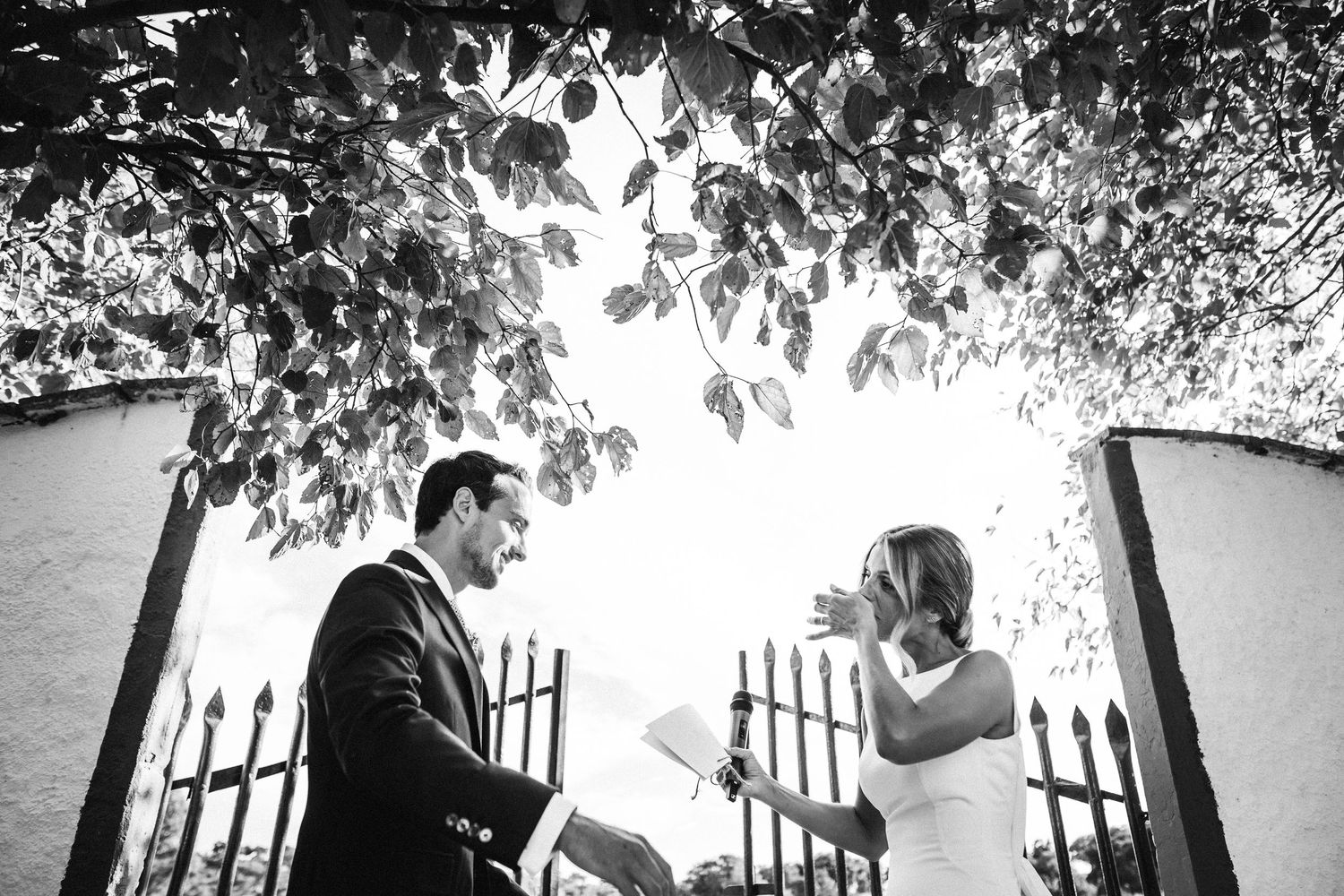 Black and white wedding portrait under tree branches creating natural framing.