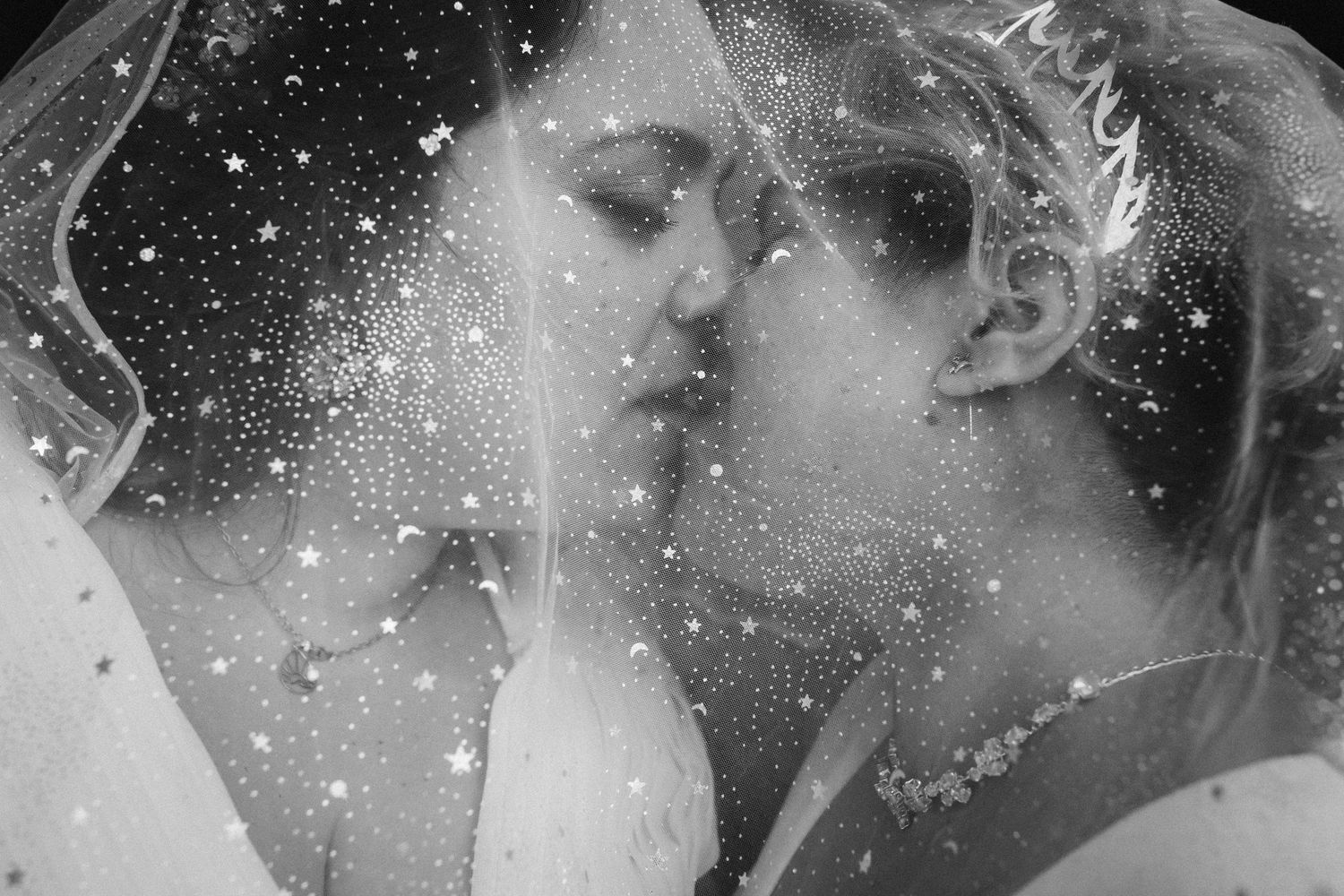 A romantic black and white wedding photo with snowflake-like sparkles creating a dreamy effect.