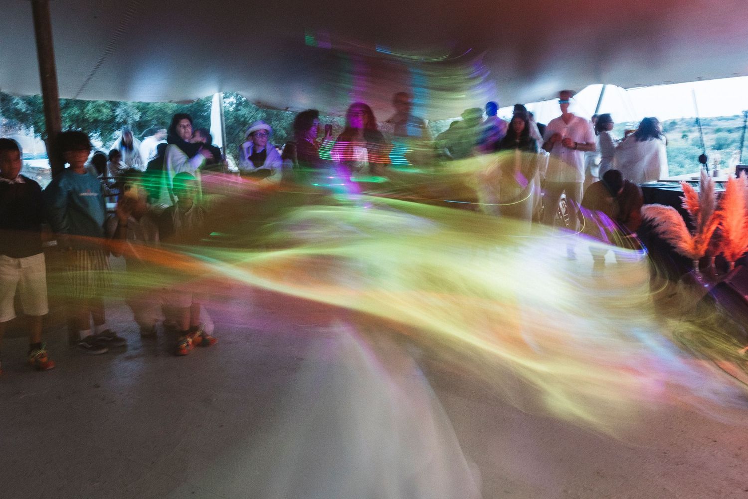 Colorful light trails and motion blur create an abstract pattern at an indoor event venue during a celebration.