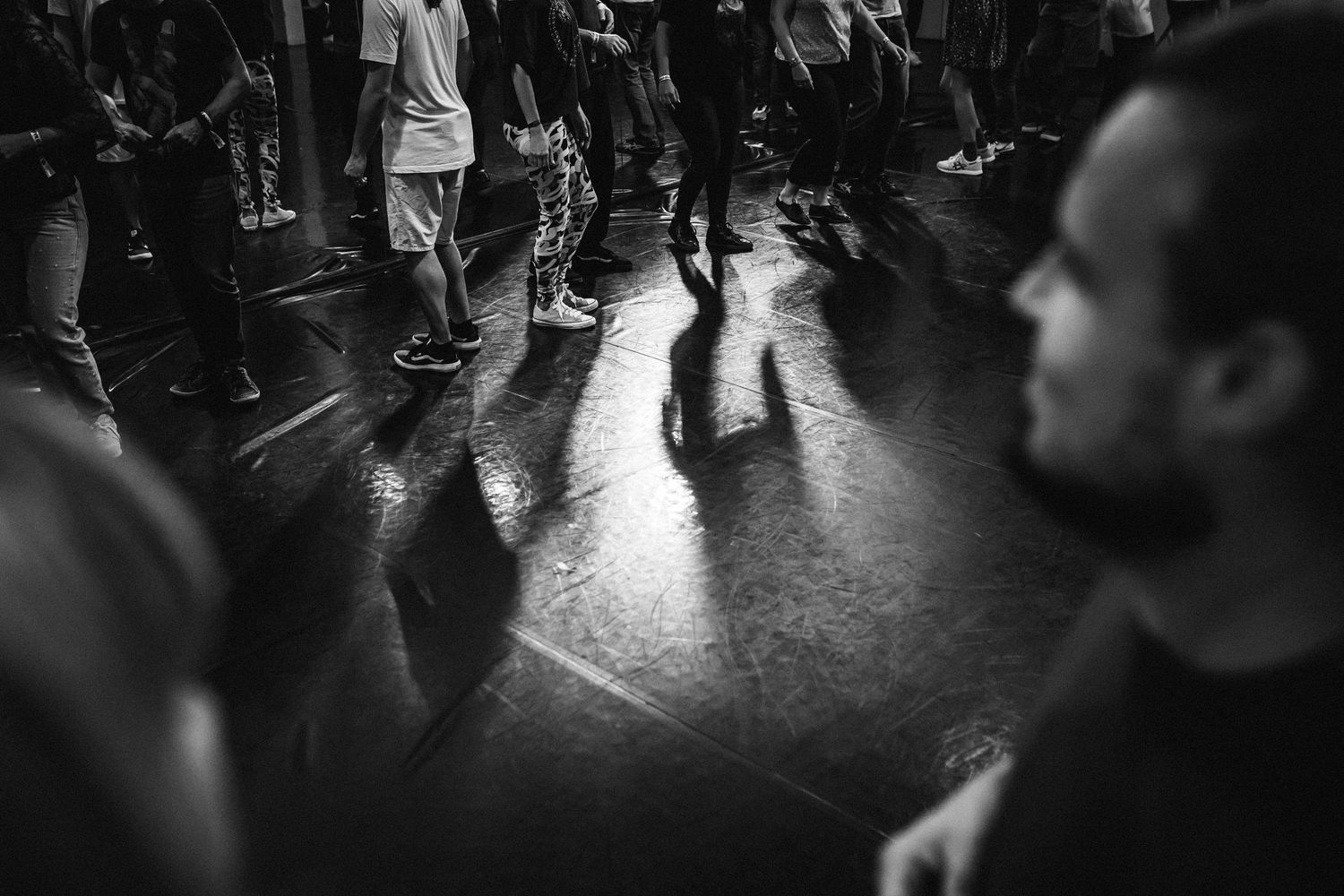 Black and white shot of dancers practicing their moves on a dimly lit dance floor.