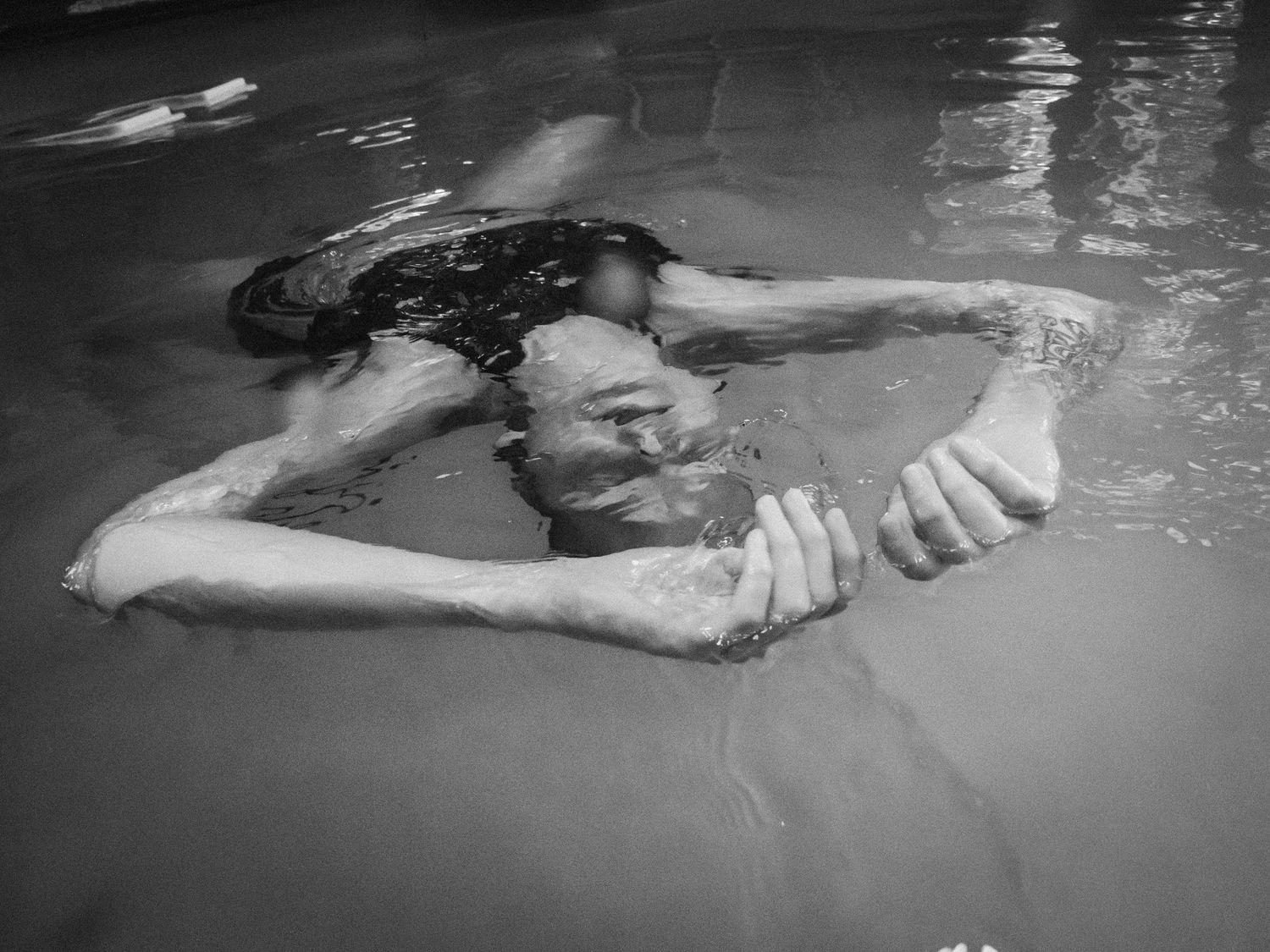 Black and white photographs showing figures submerged in water creating rippling reflections.