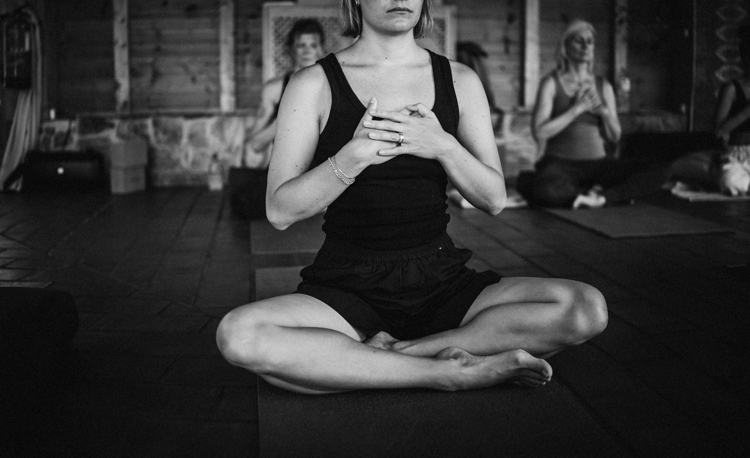Group of people practicing yoga poses on mats in a dimly lit studio space.