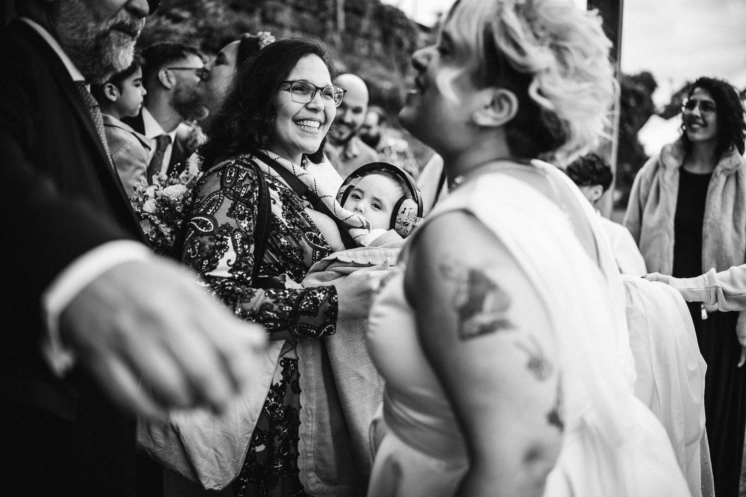 Wedding guests and couple share candid laughs during an outdoor celebration.