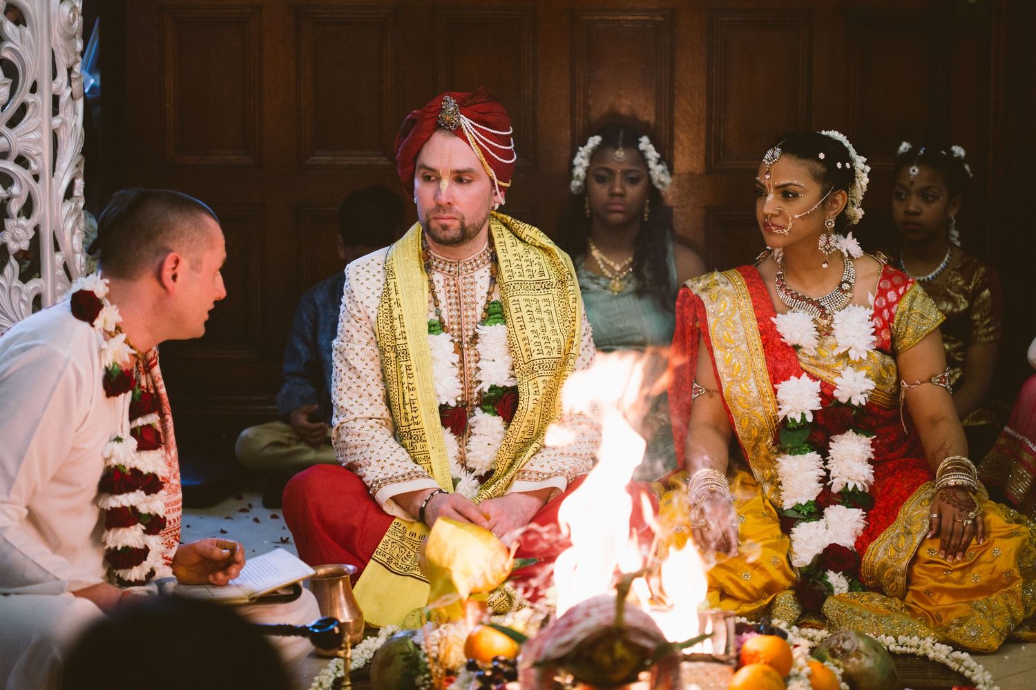 Traditional Hindu wedding ceremony with guests gathered around sacred fire during religious rituals.