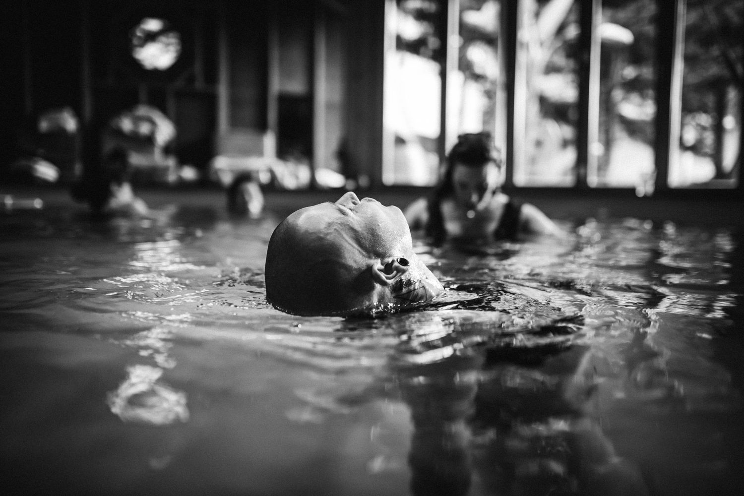 Dark silhouettes moving through water in moody black and white photography.