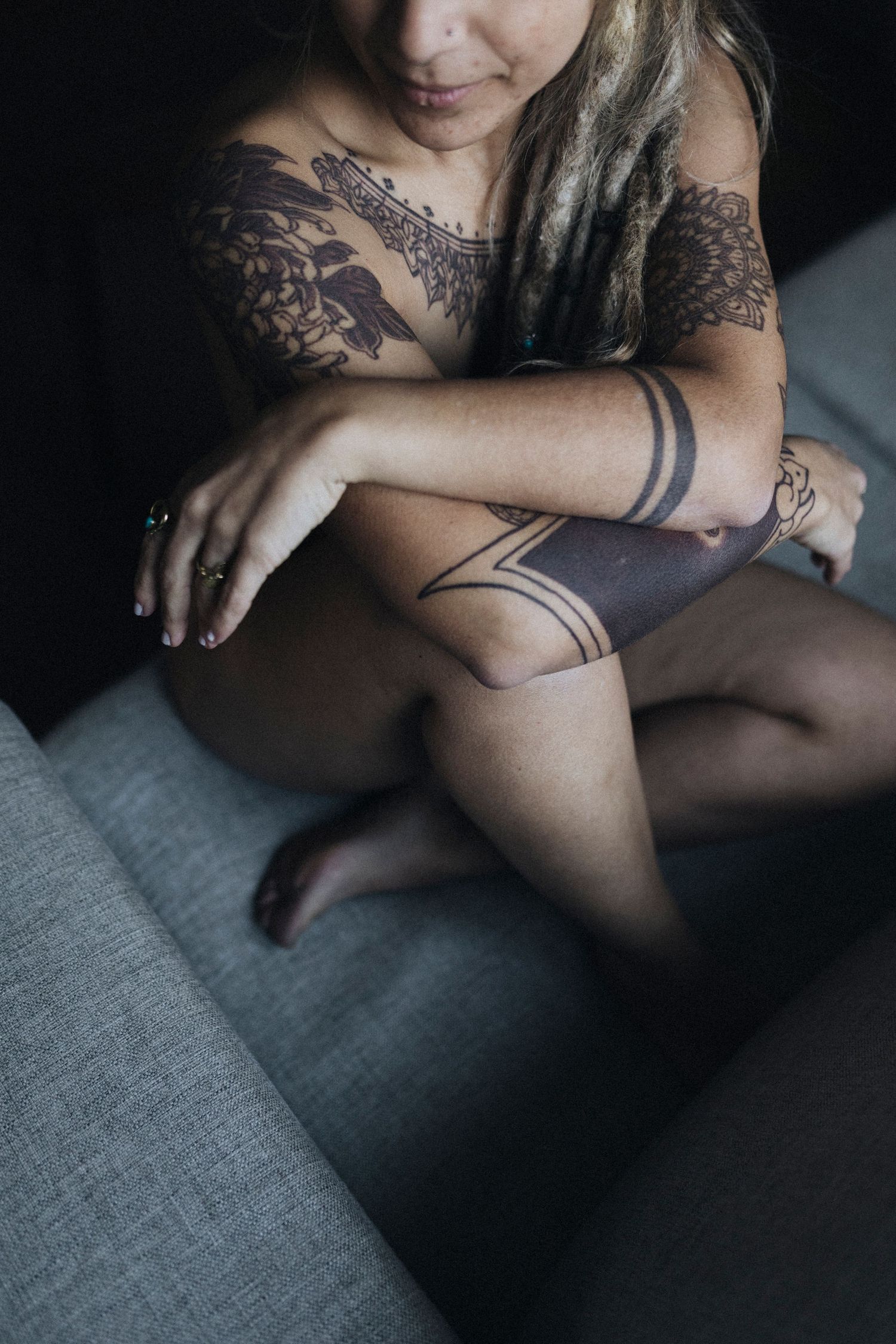 Artistic detail shot of tattooed arms crossed over dark fabric.