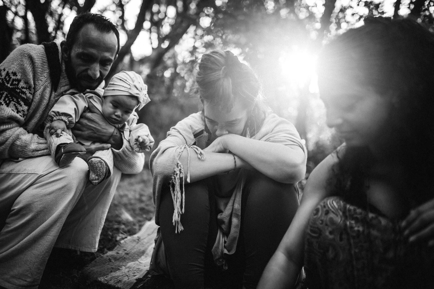 Group enjoying laughter and conversation in sunlit forest setting.