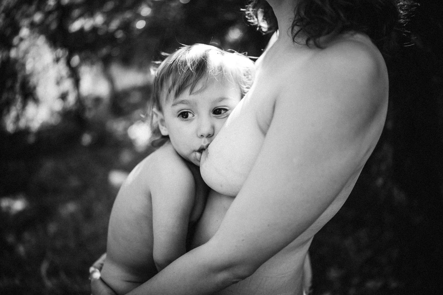 Black and white artistic photograph of a tender moment between parent and child in nature.