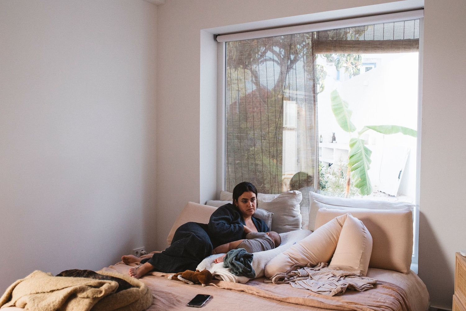 A panoramic view of a bright modern bedroom with white walls, large windows, and scattered personal belongings.
