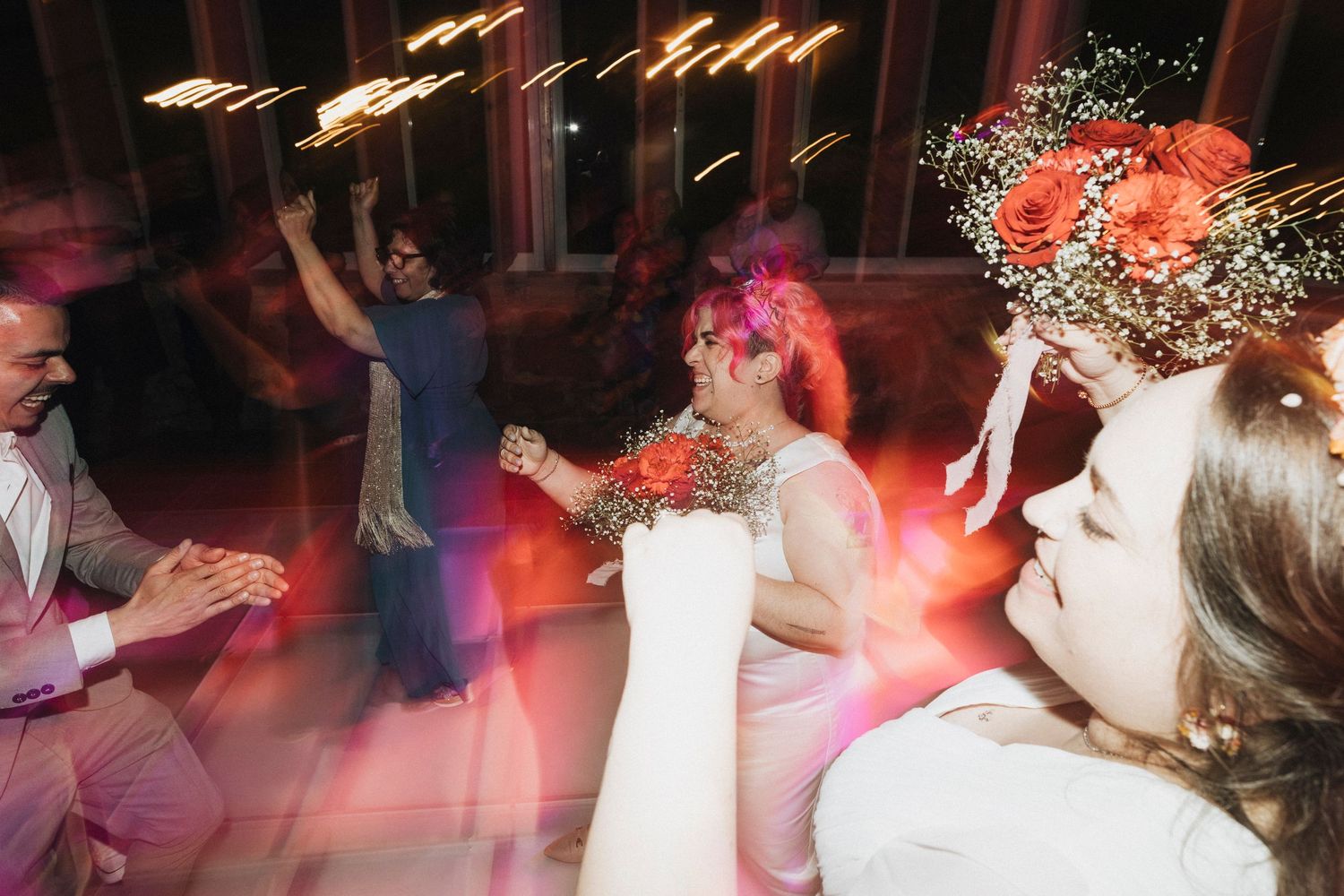 People dancing at a wedding reception with colorful lighting and decorations creating a festive party atmosphere.