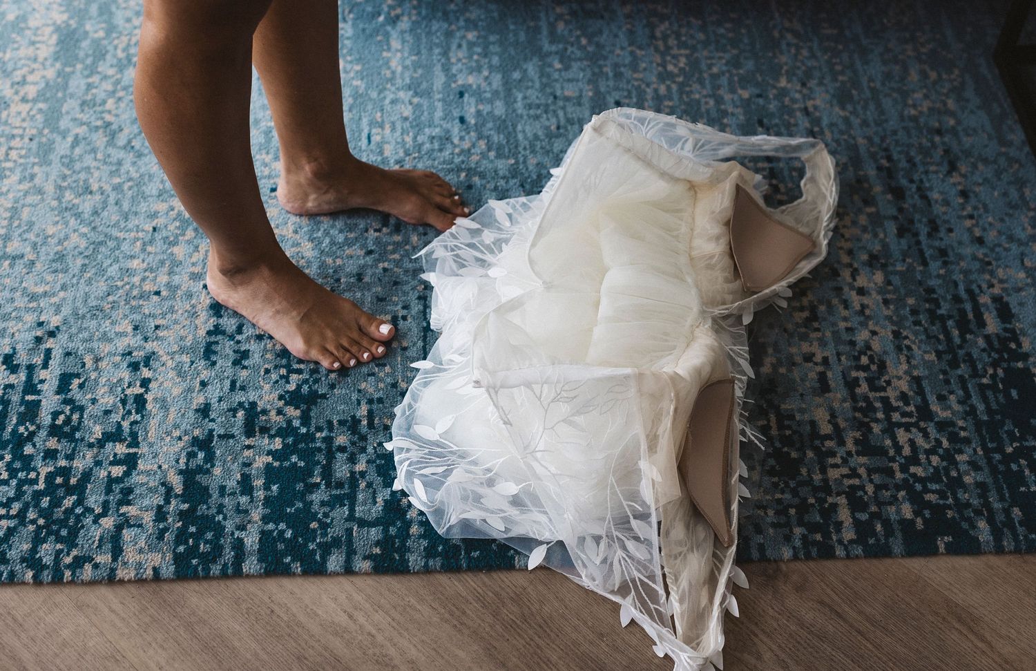 Close-up view of white tulle dress fabric against blue carpeted floor during a performance.