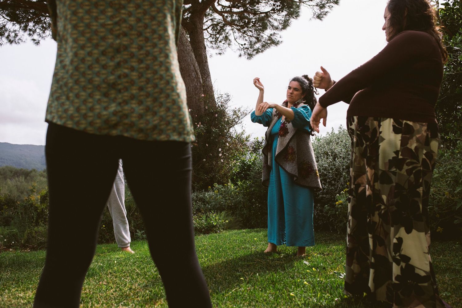 Group gathering in an outdoor grassy field with mountains visible in background.