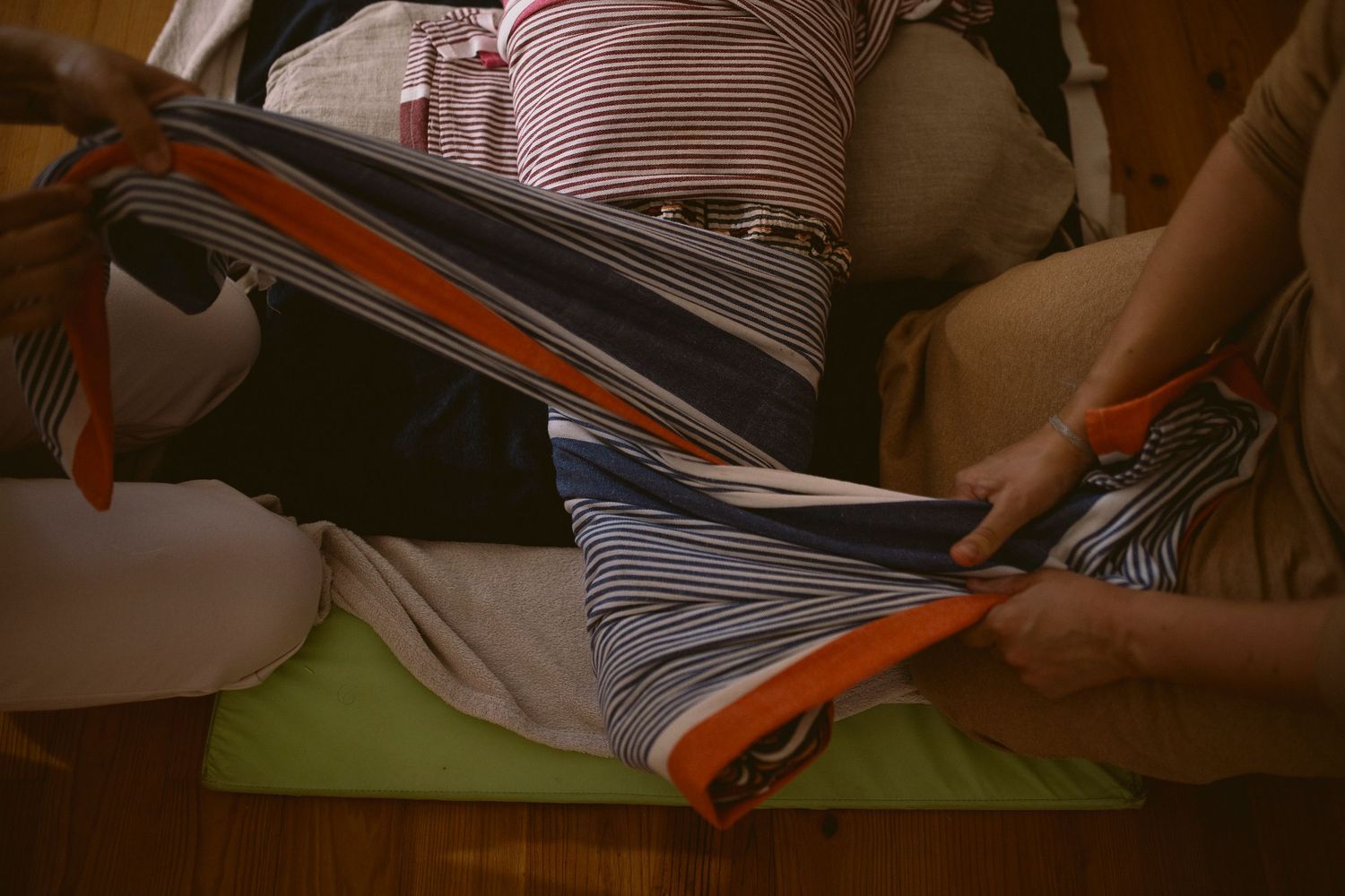 Person reading a book while lying down on a couch with striped cushions.