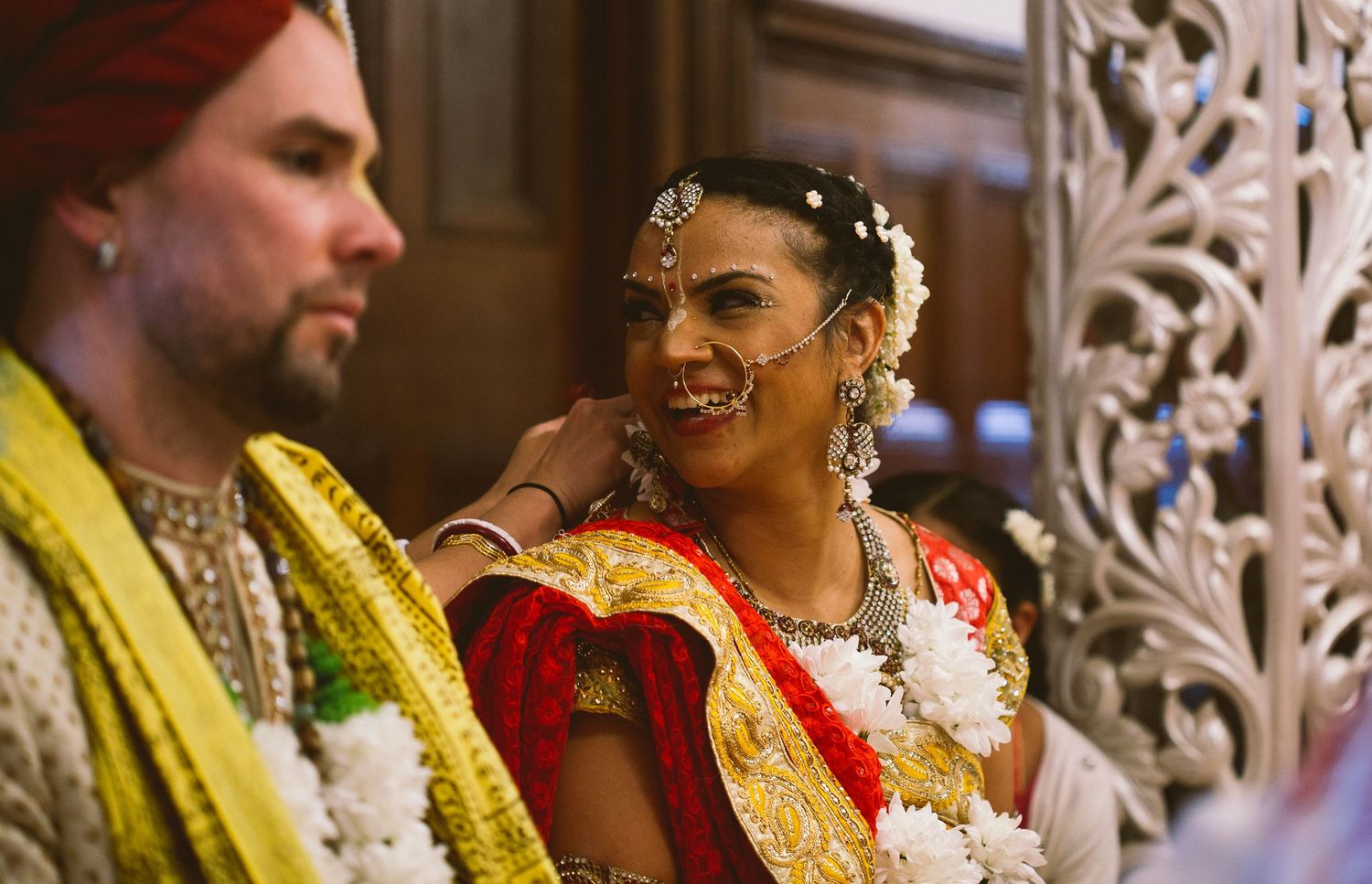 Traditional Indian wedding ceremony with decorative white panels and guests in vibrant yellow and red attire.