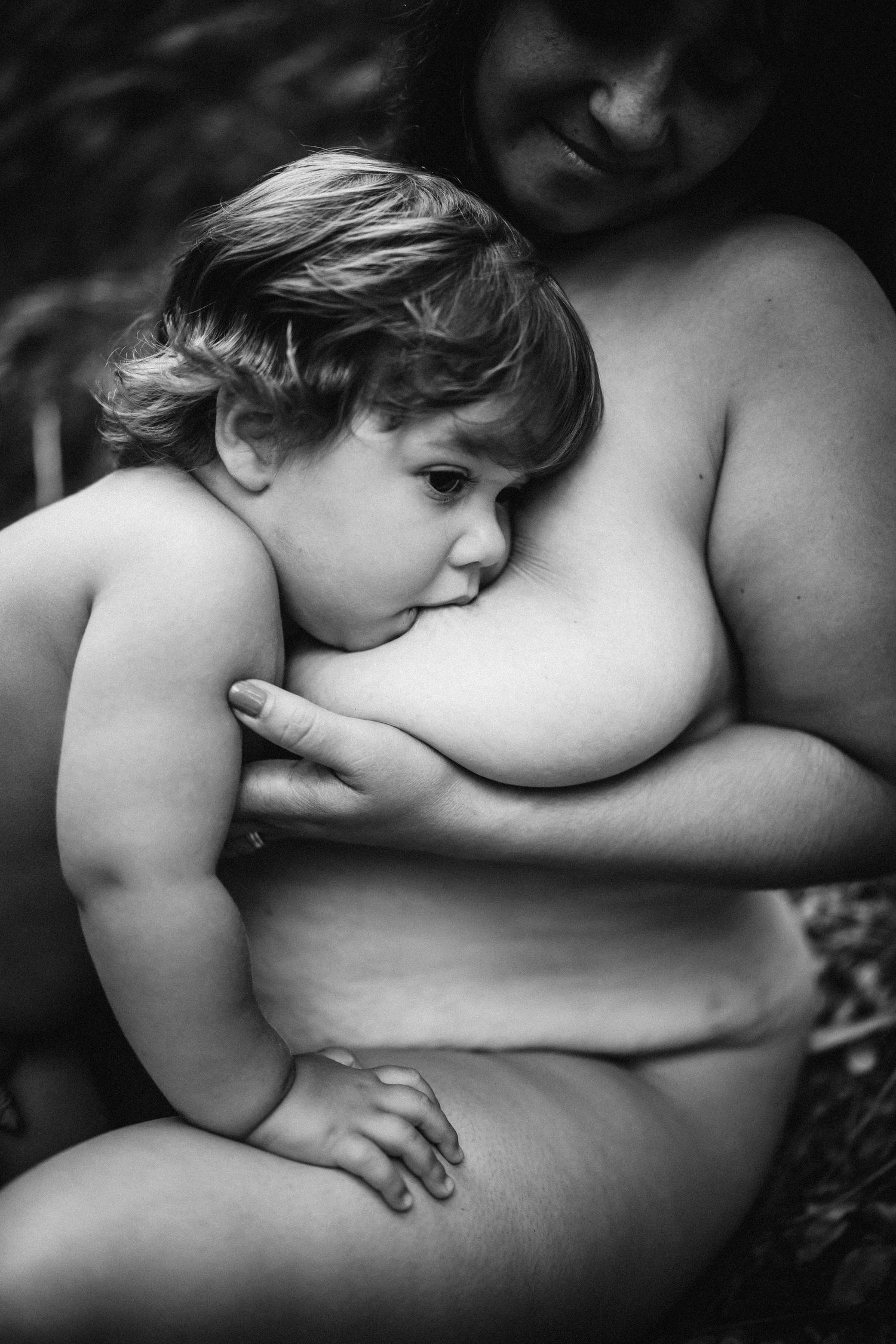 Intimate black and white photography showing gentle maternal bonding moment.