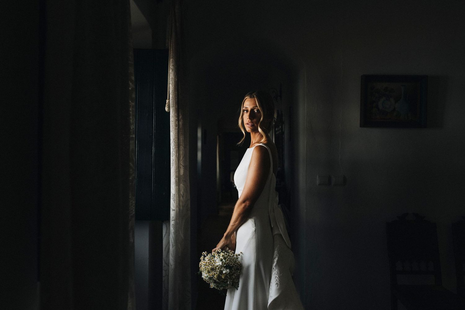 A romantic wedding couple shares an intimate moment in a dark, moody setting.