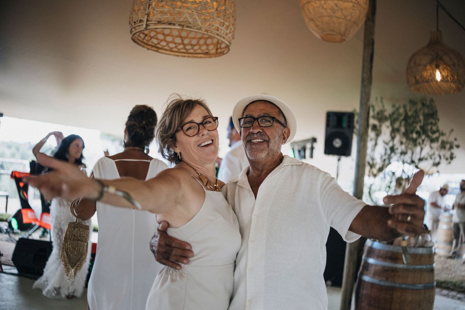 Wedding celebration candid moments showing guests dancing and embracing at an indoor reception.