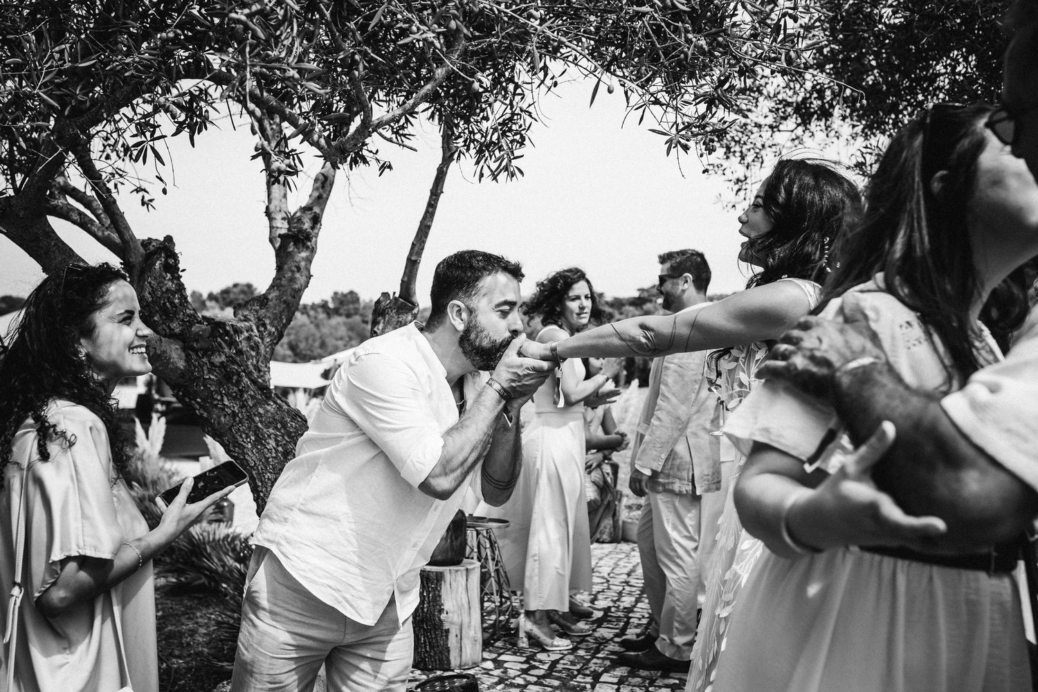 Black and white photos showing people celebrating outdoors under trees at a gathering.