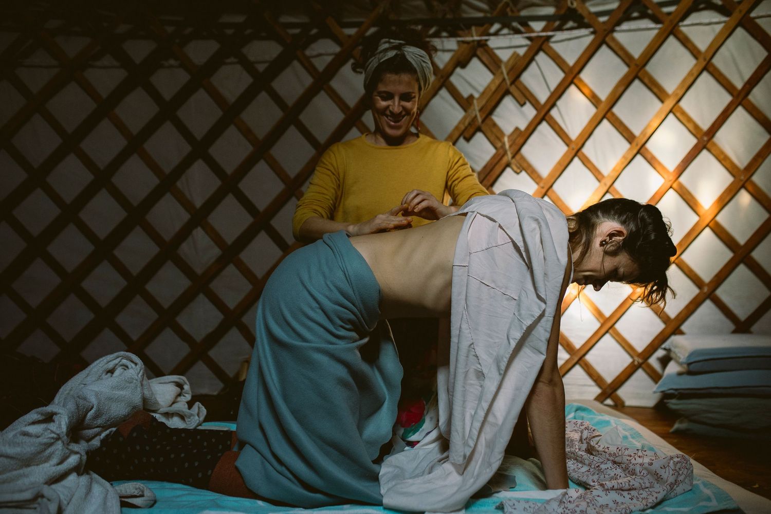 Medical professionals assist a patient on a hospital bed with a lattice pattern wall in the background.