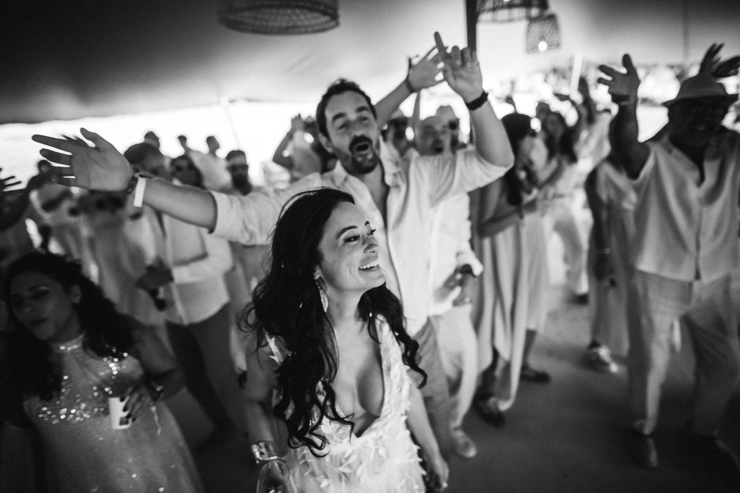 Black and white photo of a wedding reception dance floor with people dancing and celebrating joyfully.