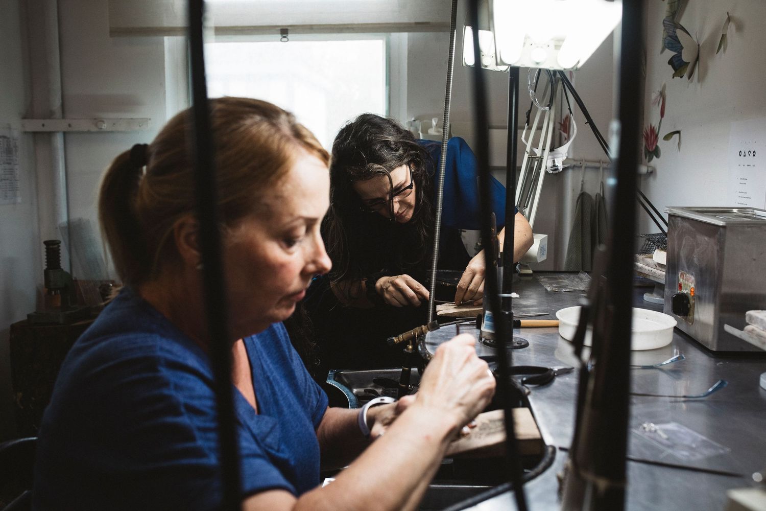 A person in a blue shirt works at a microscope station in a laboratory setting.