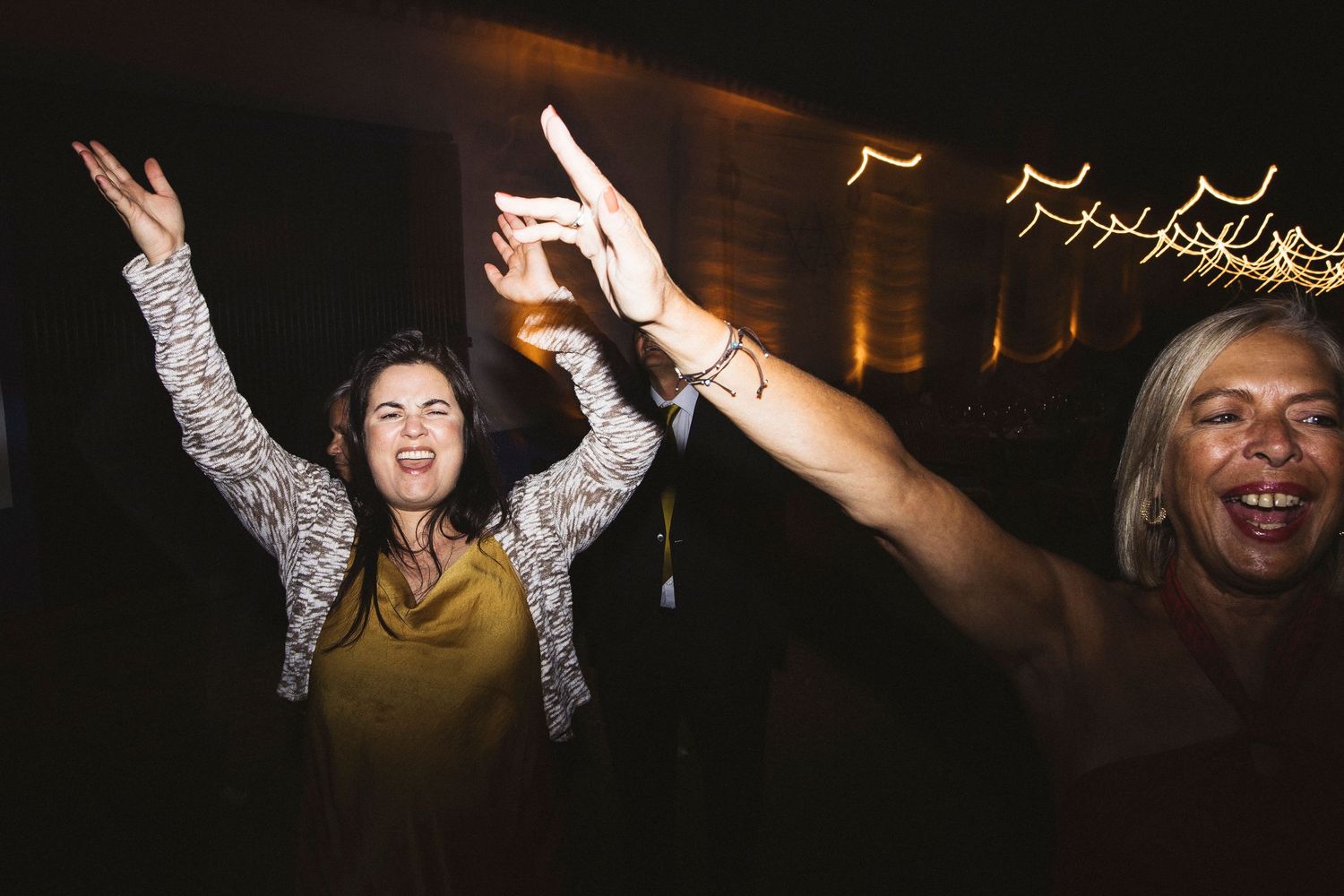 People dancing and celebrating at a nighttime party with blurred lights in the background.