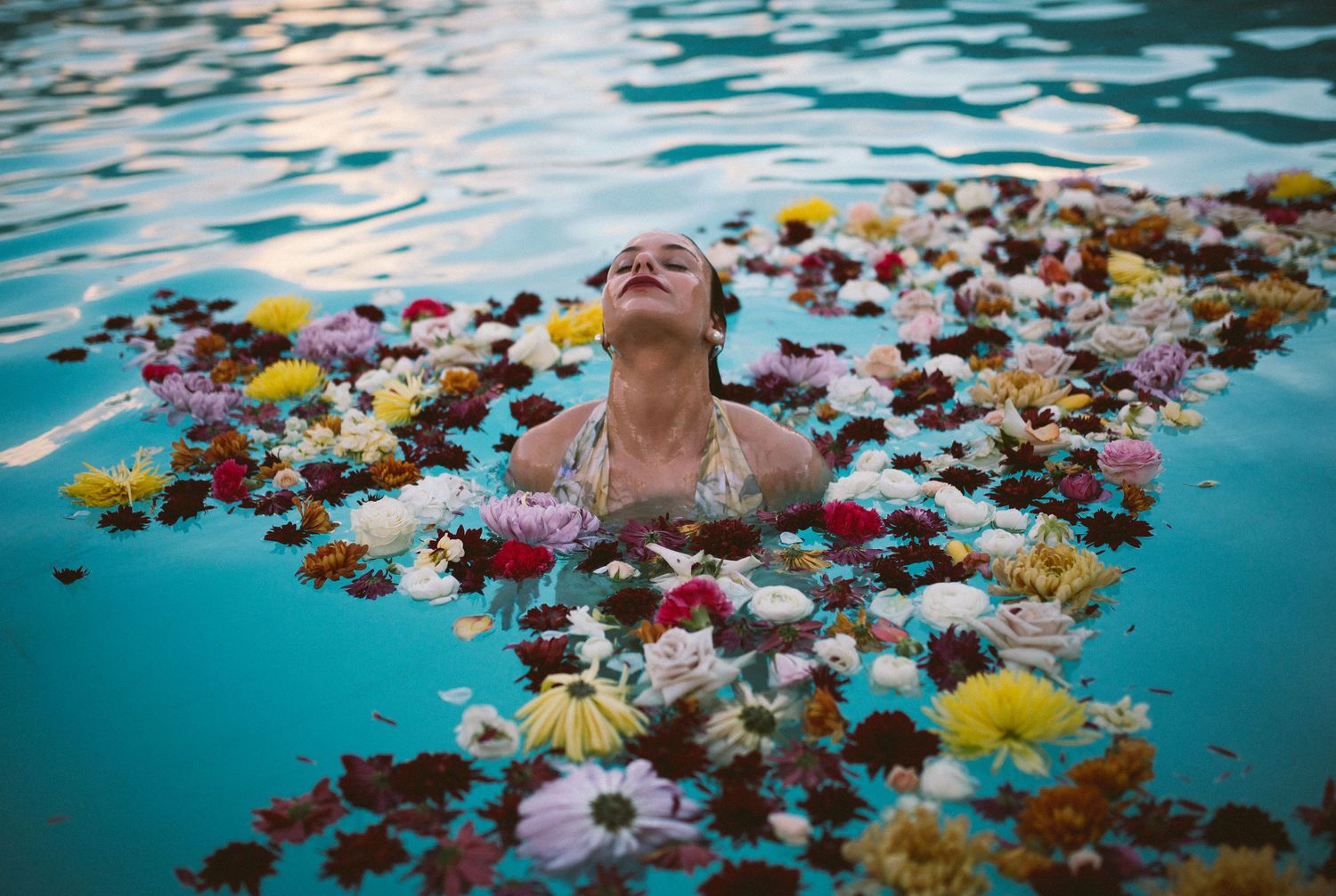 Colorful flowers float on turquoise water in an artistic spa setting creating a serene and dreamy atmosphere.