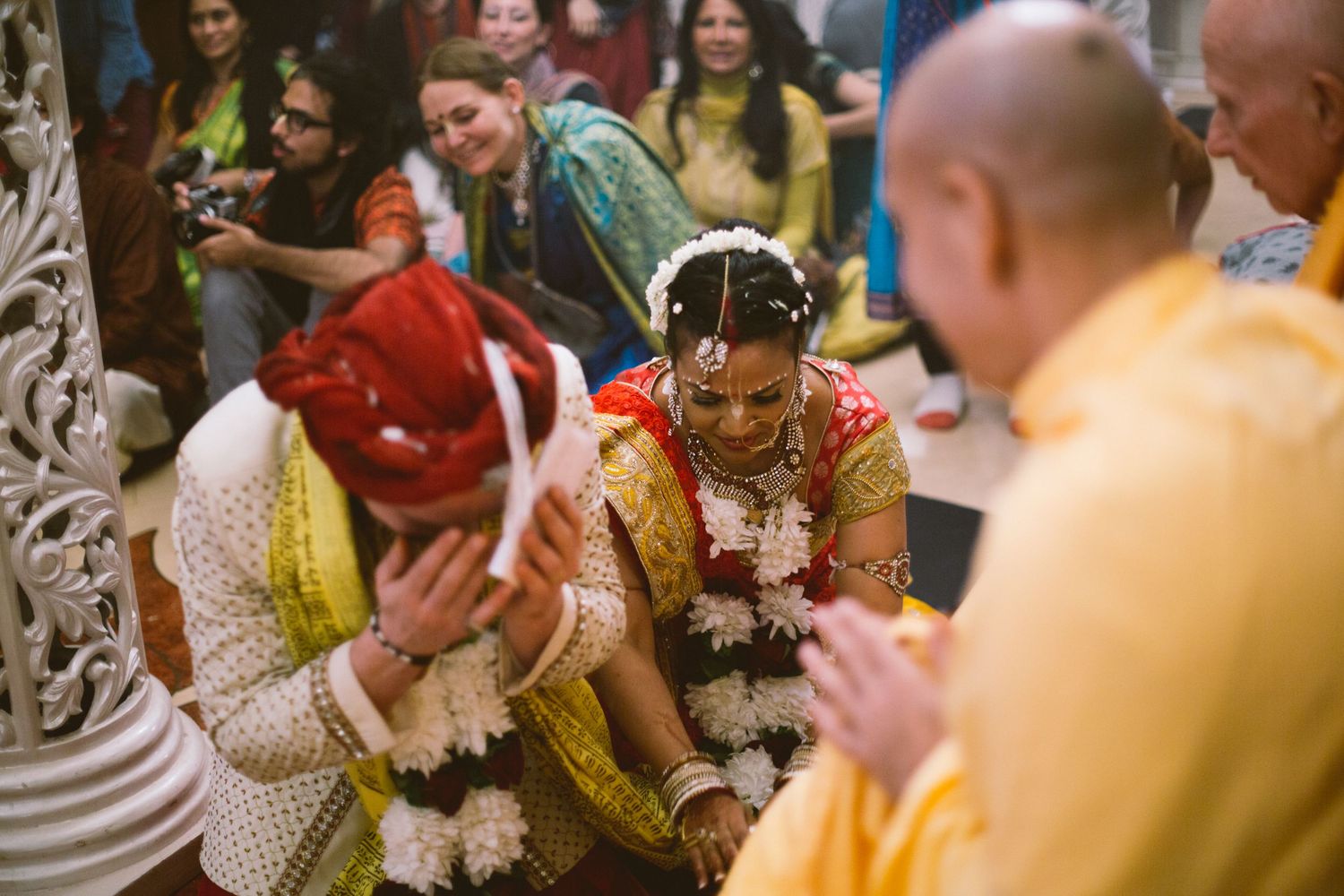 Guests in traditional Indian wedding attire participate in a ceremony with floral garlands and cultural customs.