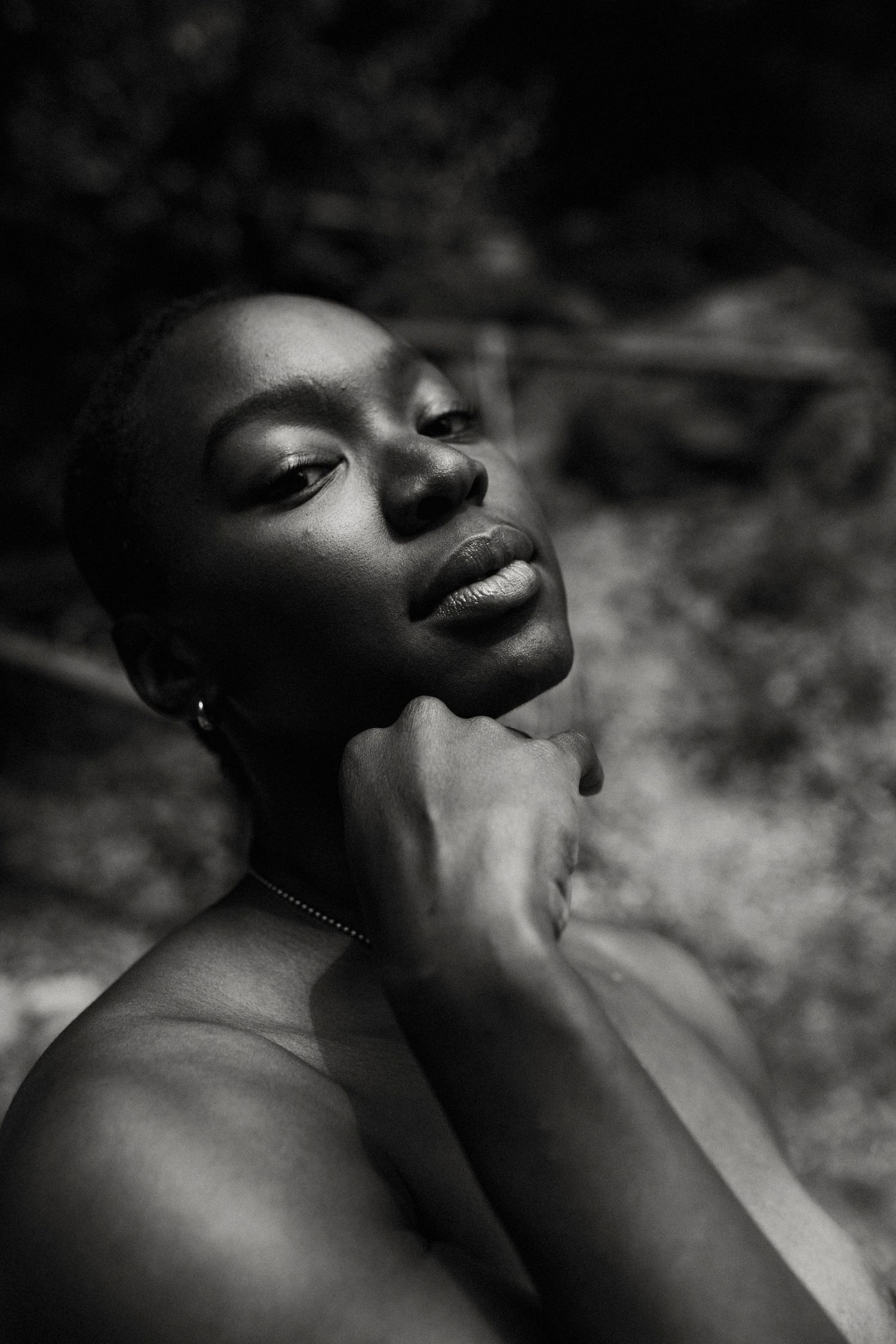 Dramatic black and white portrait photograph with soft lighting capturing an intimate artistic moment against dark background.