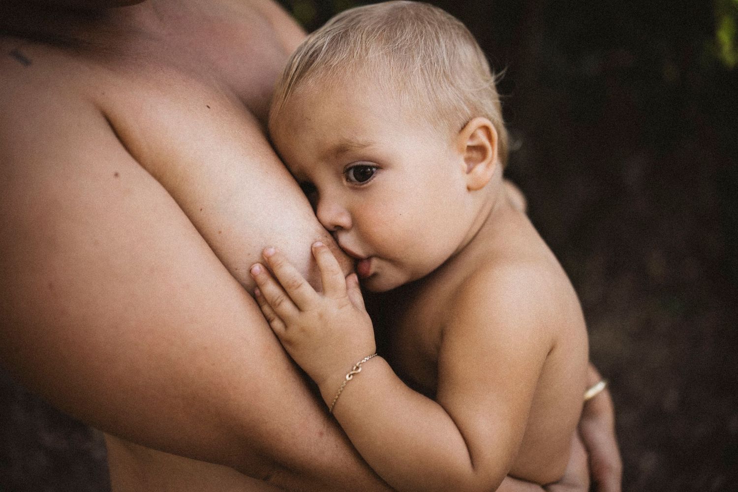 Tender breastfeeding moment captured in natural light with soft focus.