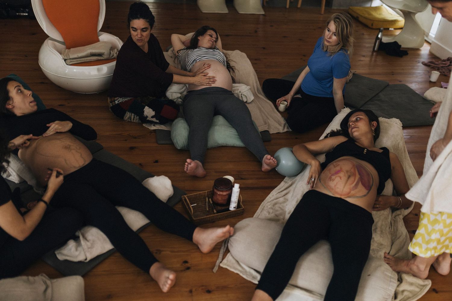 Group of people lying on wooden floor during a performance or workshop session.