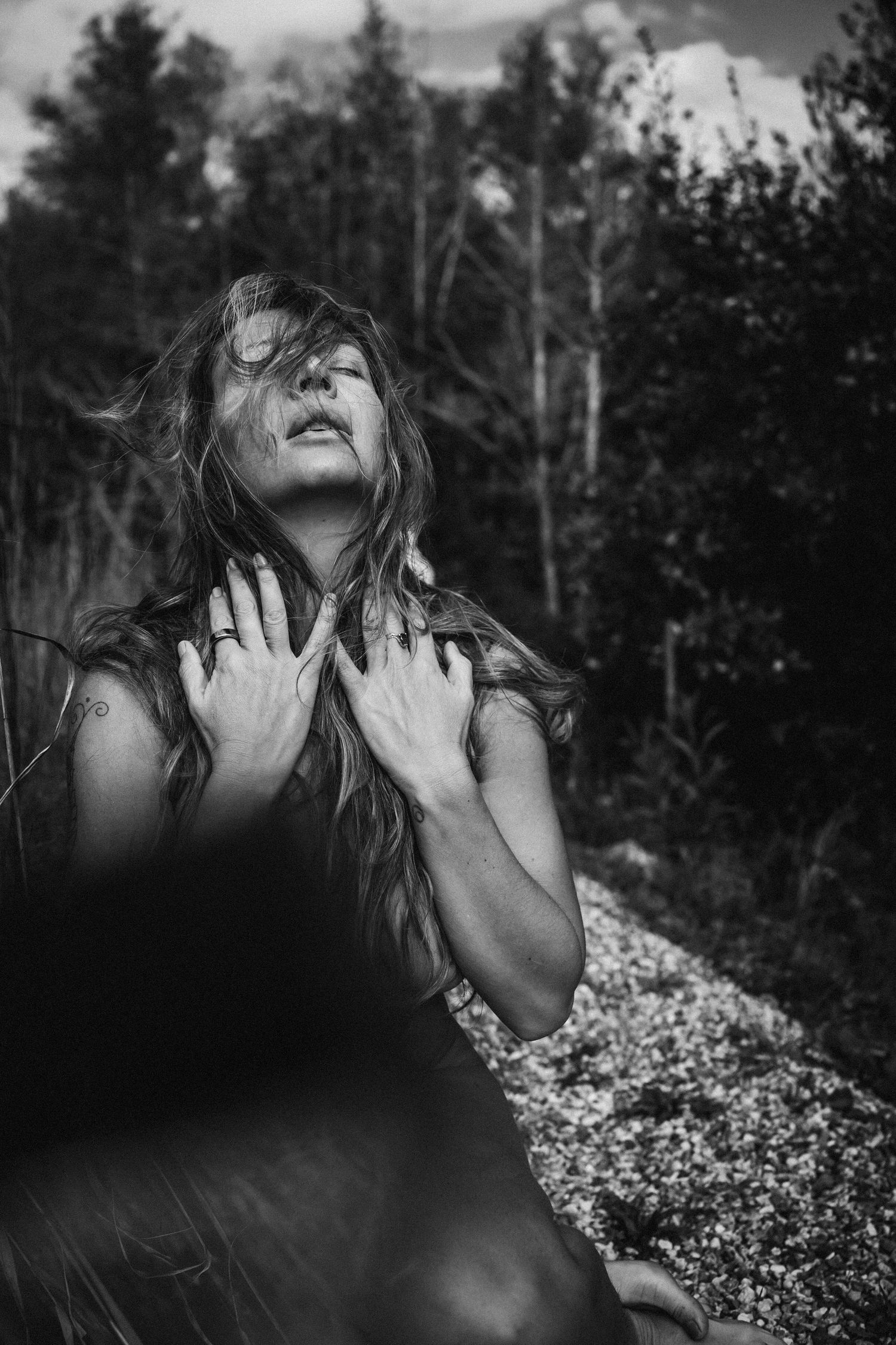 A black and white artistic portrait sequence showing a person with flowers in a dramatic outdoor pose against trees.