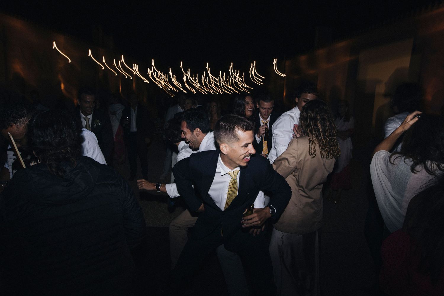 Dark and moody reception scene with dancing guests creating silhouettes.