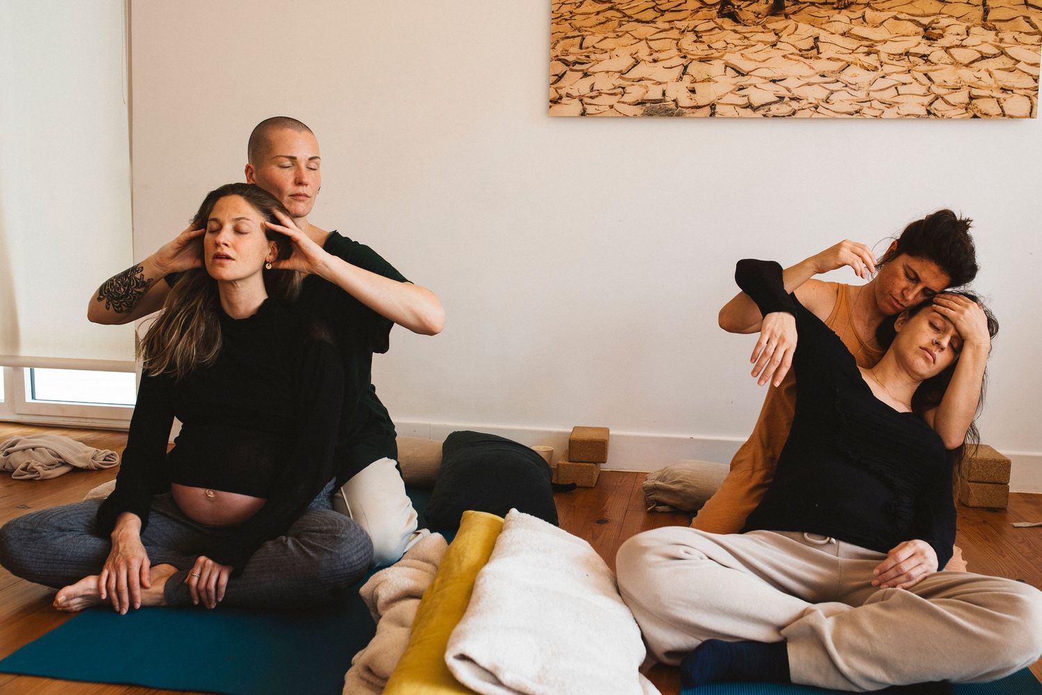 Students practicing partner yoga and movement exercises in a bright studio space.