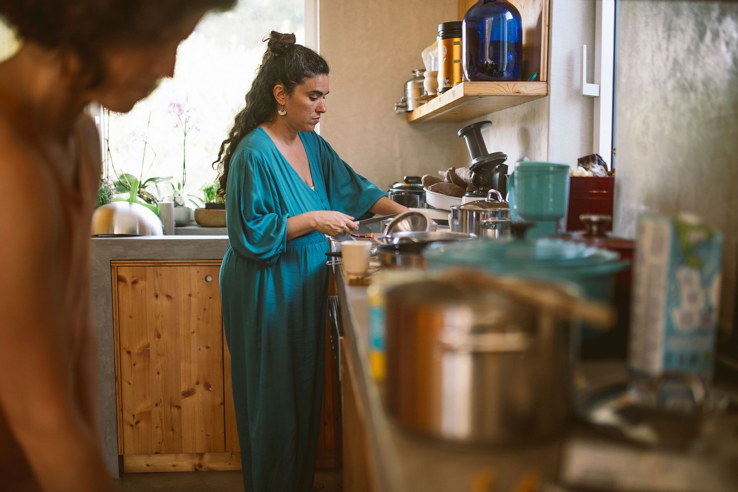 Kitchen scene with teal accents and warm natural lighting through windows.