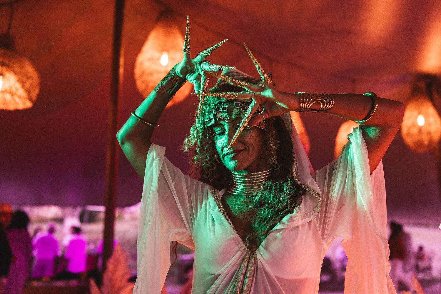 Dancers performing under dramatic red and green stage lighting with flowing white fabric.
