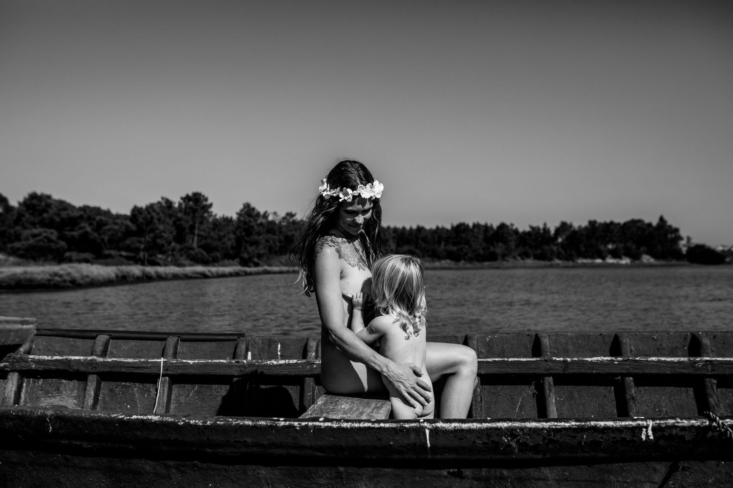 A black and white photo series showing a person sitting on a wooden dock by a tranquil lake at sunset.
