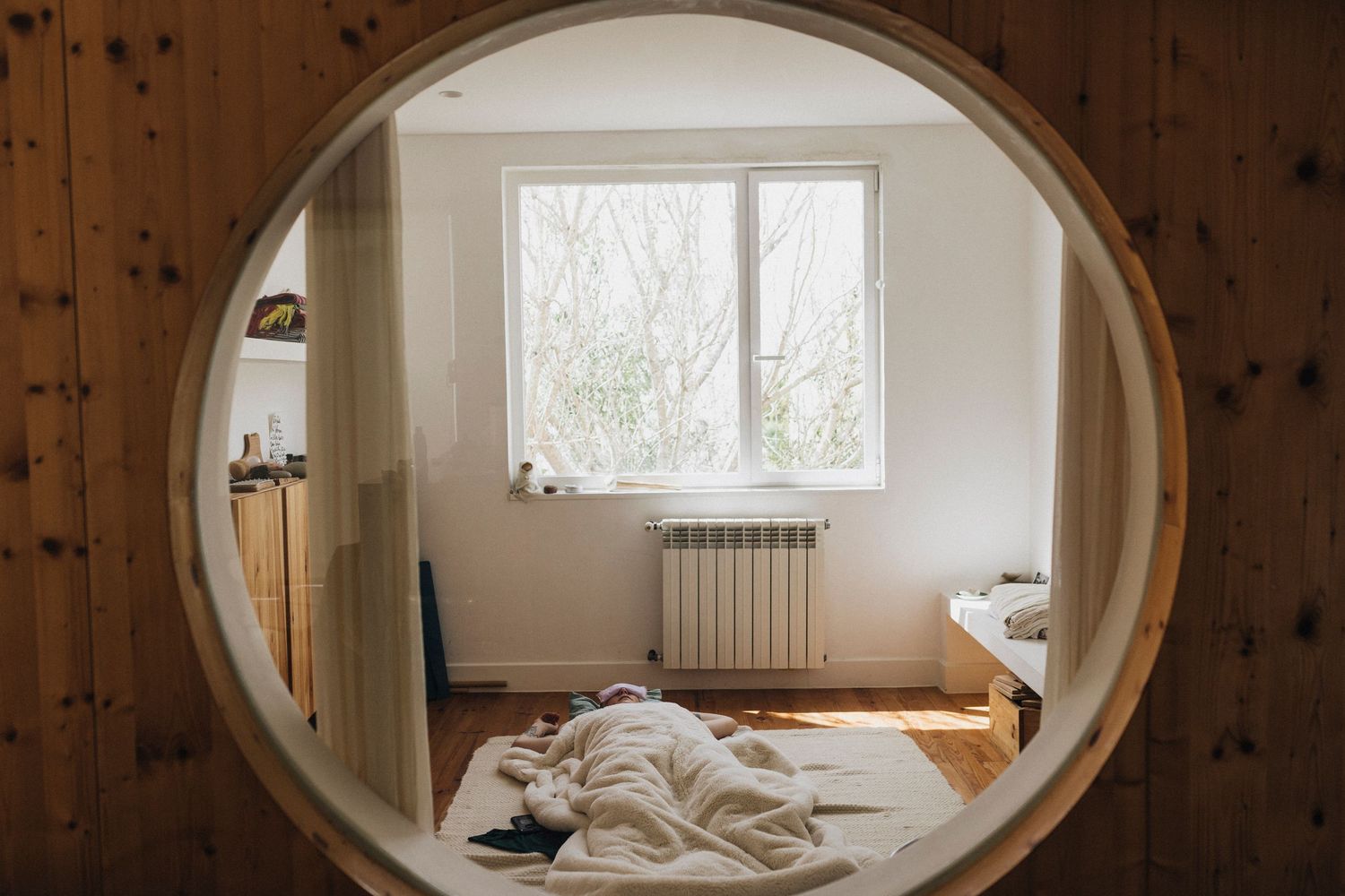 Minimalist interior room with wooden walls and oval window frames creating symmetrical composition.