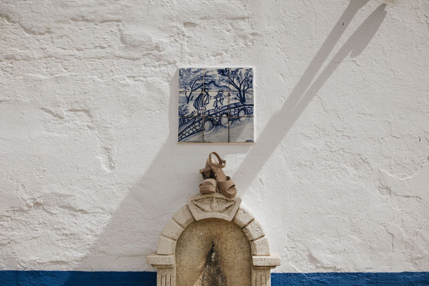 A historic stone building with white walls and arched architectural details features mounted decorative elements.