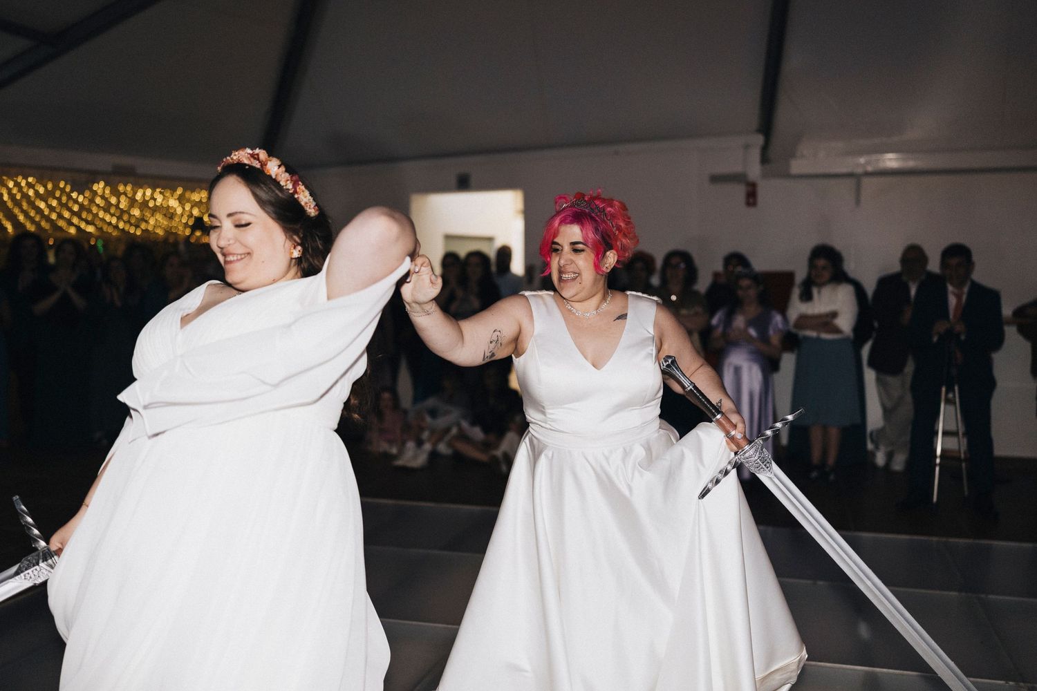A group of dancers in flowing white dresses perform a synchronized dance routine on stage.