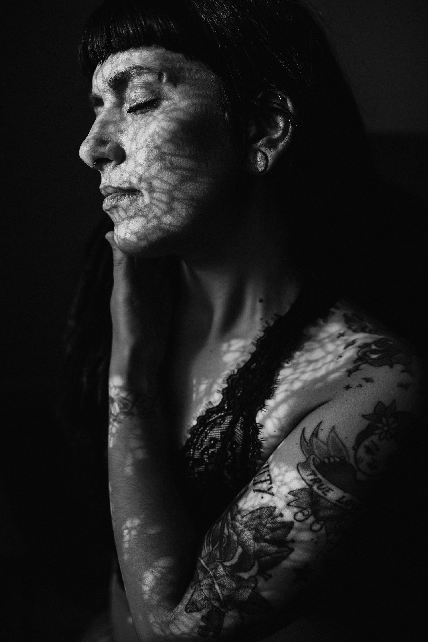 Artistic black and white portrait series showing delicate lace shadow patterns cast across skin in dramatic lighting.