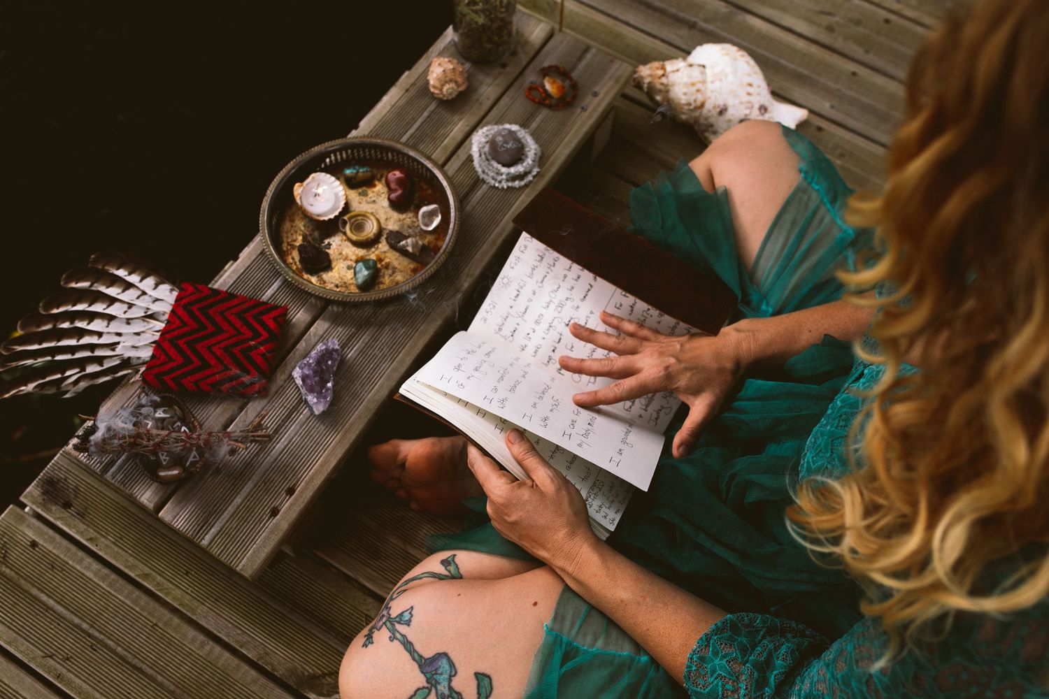 Hands working on crafts and materials on a wooden table surface.