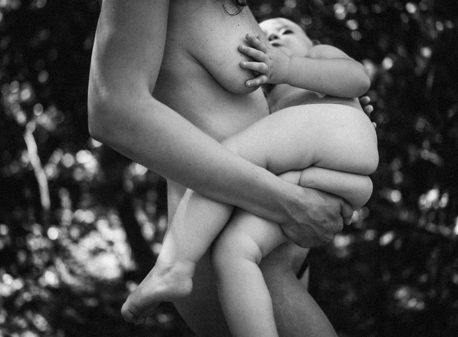 Black and white image capturing gentle embrace during breastfeeding moment.