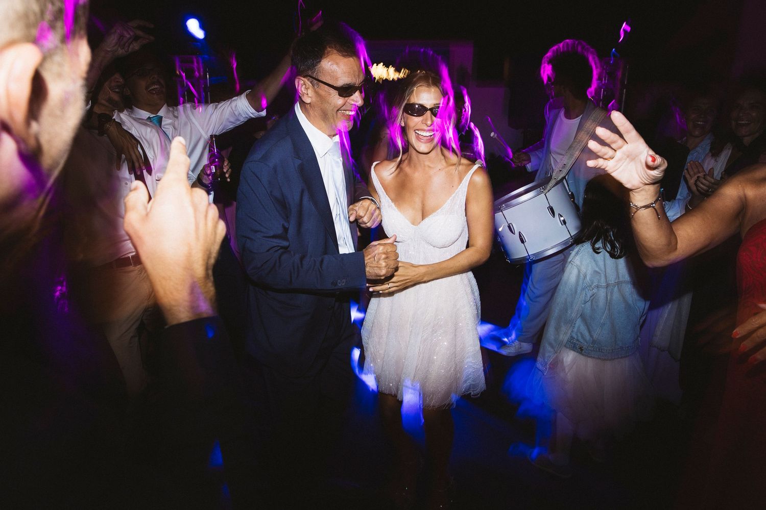 Wedding party dancing in a dark room with purple and blue lighting effects.
